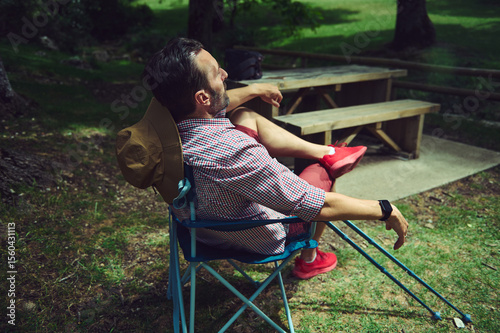 Man Relaxing Outdoors in a Forest Environment Near a Wooden Picnic Table