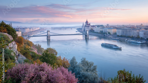 Fog is covering the danube river with the hungarian parliament building and the széchenyi chain bridge at sunrise