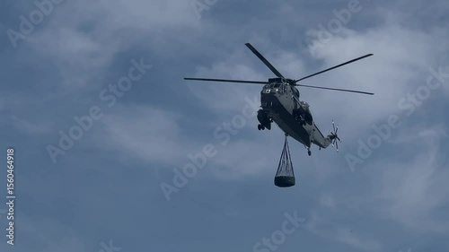 A Westland Sea King Helicopter approaching with cargo net slung below. Filmed at Portland UK.