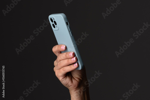 Wallpaper Mural Hand Holding Smartphone with Blue Case Against Dark Background Torontodigital.ca