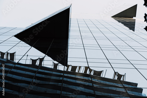 Bold triangular structures cut through the urban sky, forming abstract surfaces and dynamic shadows that bring modern architecture’s futuristic geometry into focus under vibrant daylight conditions.