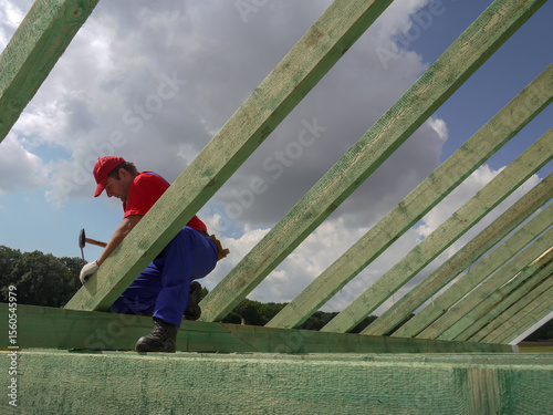 Construction Worker Securing Trusses on Wooden Roof Framework Outdoors