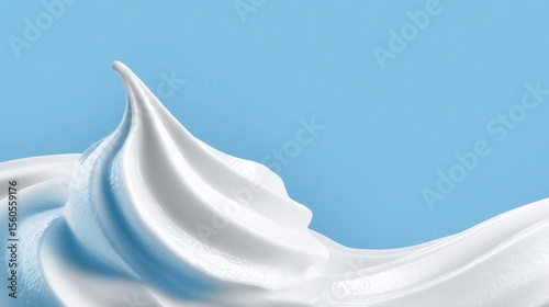 Swirls of creamy white topping cascade in graceful waves contrasting with a cool blue backdrop evokes desserts and airy lightness