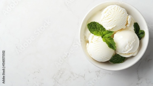 Three scoops of vanilla ice cream in a white bowl, garnished with fresh mint leaves, on a white marble surface (1)