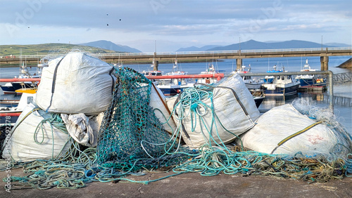 Huge piles of fishing nets in on a dock in a small fishing village Portmagee in Ireland. The scene reflects the busy activity of traditional fishing industry by the Atlantic ocean.