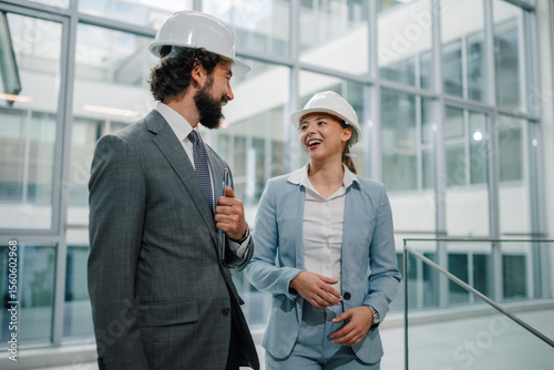 Smiling architects walking and talking about project in modern office building