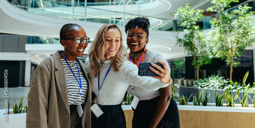 Three businesswomen taking a selfie in a modern office space