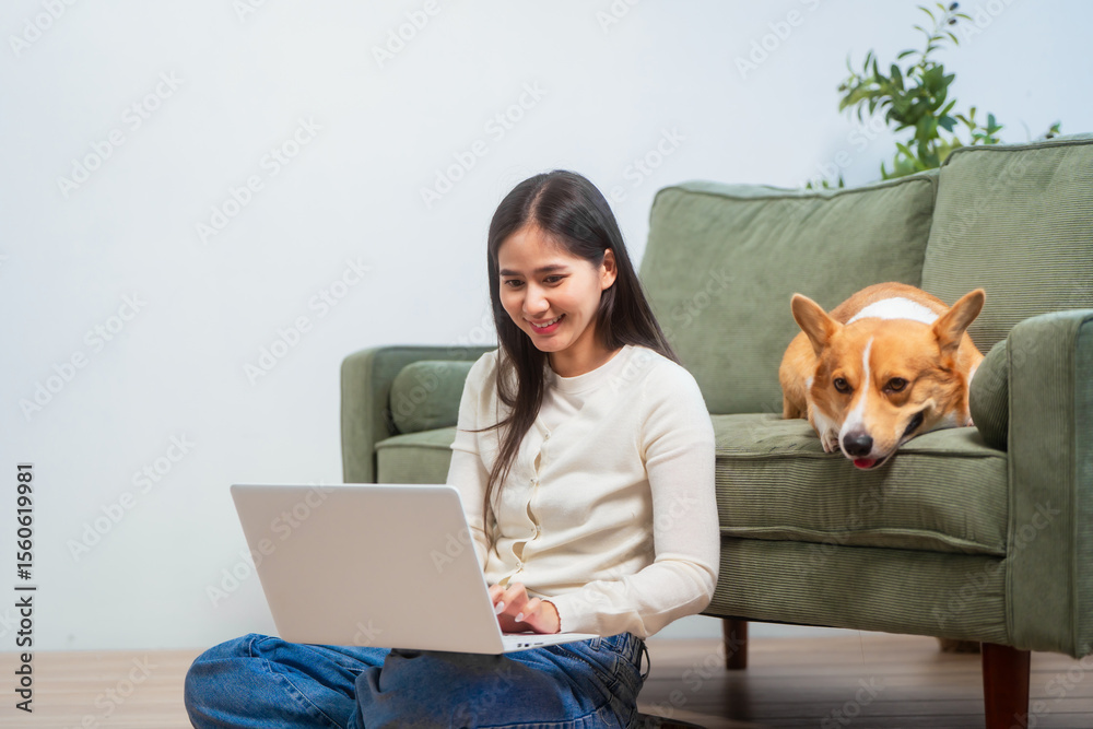 Asian young woman sits on the floor beside her sofa, gently stroking her Corgi dog head relax at home, reflecting warmth, pet lover, the comfort of home life. Asian young woman sits on the floor beside her sofa, gently stroking her Corgi dog head relax at home, reflecting warmth, pet lover, the comfort of home life.