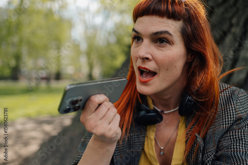 Businesswoman recording voice message using smartphone in park