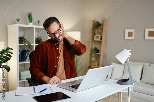 Man experiencing neck pain while working at desk