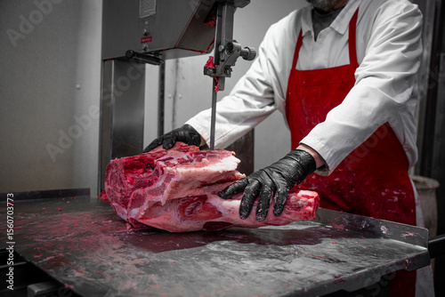 Butcher Cutting Raw Beef with Electric Saw in Meat Processing Facility

