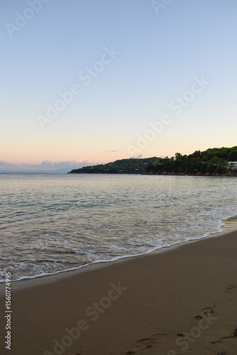 Wallpaper Mural Picturesque sunset on a sandy beach in Skiathos, Greece. Gentle pastel colours glow in the sky above calm beach waves, backdropped by Greek island landscapes. Torontodigital.ca