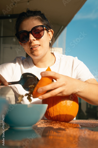 Woman scooping out pumpkin to prepare flower arrangement