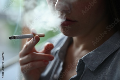 Woman smoking cigarette indoors, closeup. Bad habit