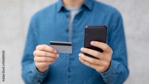 Close up of hands holding credit card  smartphone  online payment  digital transaction  blue shirt  casual