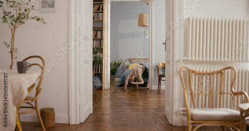 Active girl in casual clothes dancing funny dance on the floor and moves differently during her fun at home in cozy modern apartment. Dance and self-expression at home