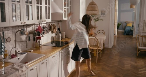 Cheerful girl in casual clothes improvises and dances in contemporary style at home in the morning in a modern cozy apartment. Dance and breakfast in the morning