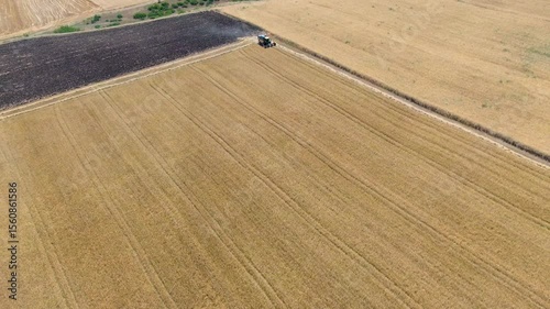 Drone footage of a combine harvesting wheat. Grain field