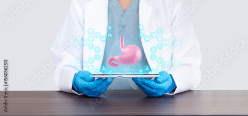Gastroenterologist with tablet showing an anatomical model and 3D hologram of the stomach and digestive system. Digestive health, prevention, diagnosis, endoscopy, and medical technology.