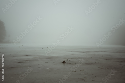 Frozen lake under thick layer of fog