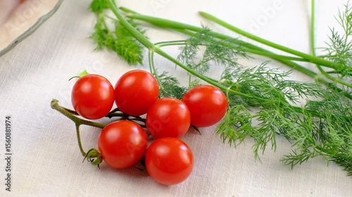 Fresh cherry tomatoes with herbs on white tablecloth for culinary inspiration