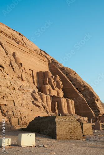 Side view of the Abu Simbel Temple at sunrise, showcasing its massive sandstone facade and colossal statues of Pharaoh Ramses II.