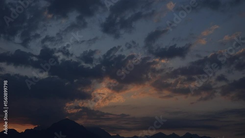 Sunrise over the mountains, sun rising from behind the mountain with colorful clouds moving, early morning video time lapse