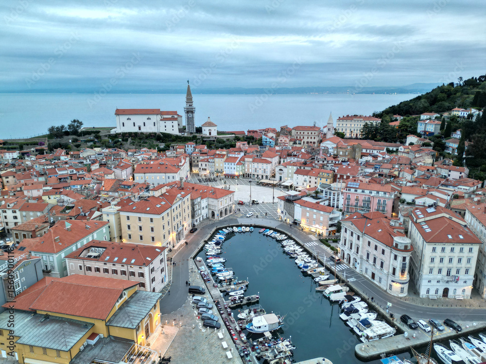 Fototapeta premium aerial view of piran slovenia, popular tourist destination on the istrian peninsula of the Mediterranean coast (europe european marina boats downtown view tower roofs sunset) blue hour beautiful
