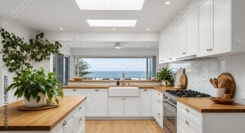 Bright modern kitchen interior with wooden countertops and ocean view through large windows