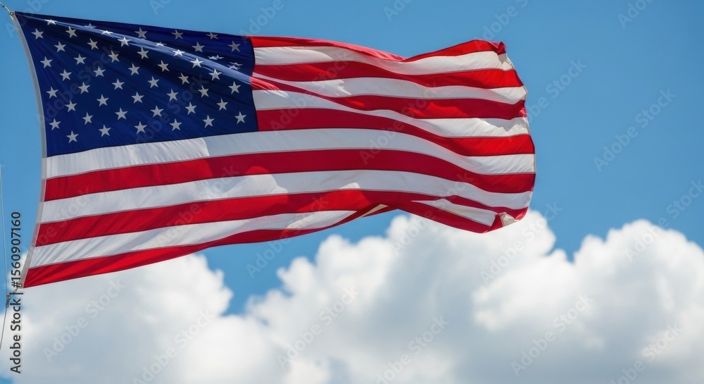 Obraz premium United States Flag Against a Bright Blue Sky with White Clouds