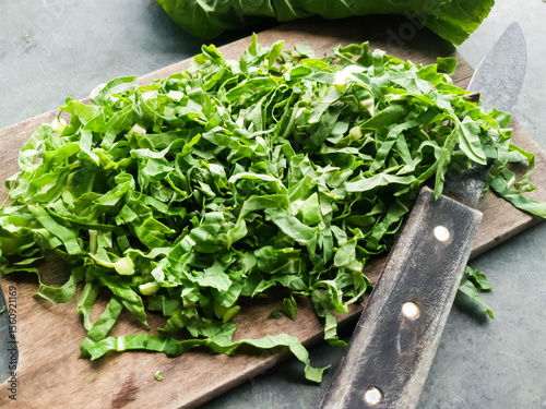 Brassica oleracea leaves, green cabbage cut chiffonade on rustic wooden board 