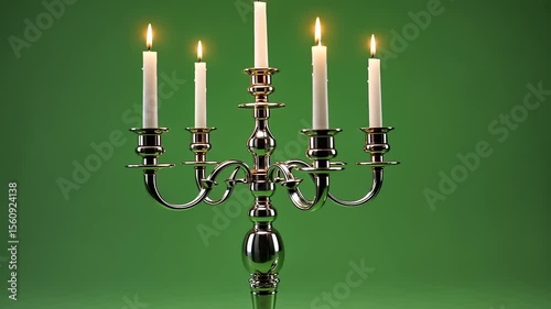 Elegant silver candelabra with five lit candles on green backdrop