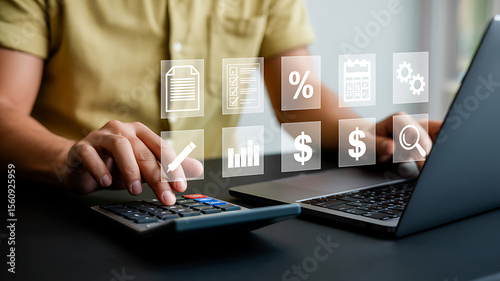 Man using calculator and laptop with financial icons floating above the devices on desk