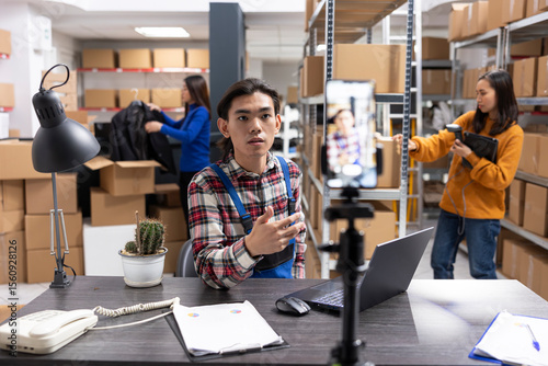 Small business owner uses a smartphone to film content inside fulfillment center, vlog highlighting inventory, order processing and local delivery services for regional online promotion.