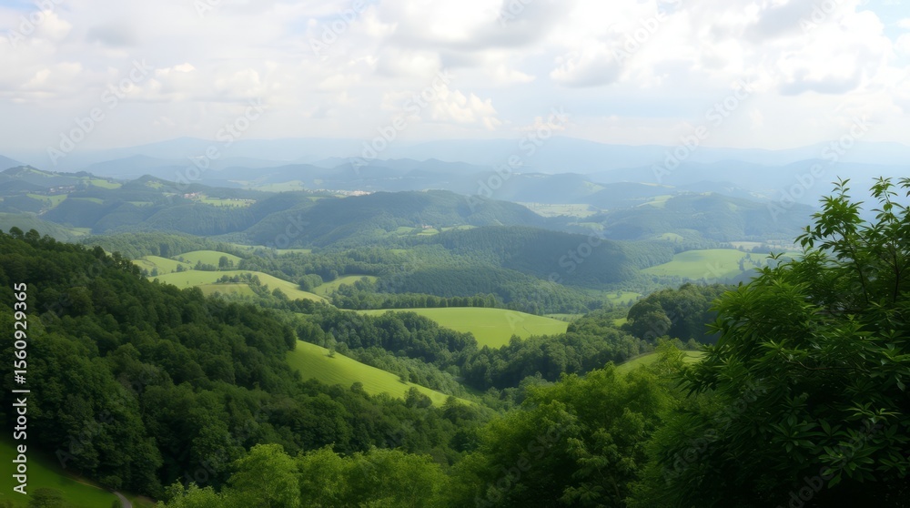 Fototapeta premium Serene Mountain Vista: Rolling hills and lush green valleys stretch out to the horizon under a partly cloudy sky, creating a breathtaking panorama of natural beauty.