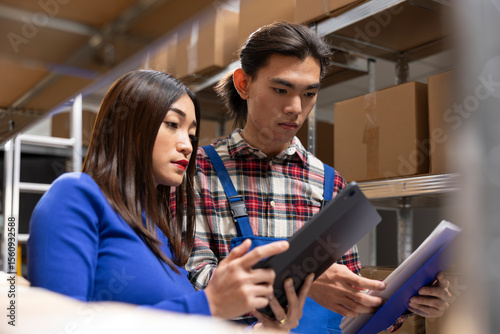 Asian employees organizing taped boxes and goods in a storage room, working on a retail small business local brand. Staff managing inventory and express delivery tasks in warehouse.