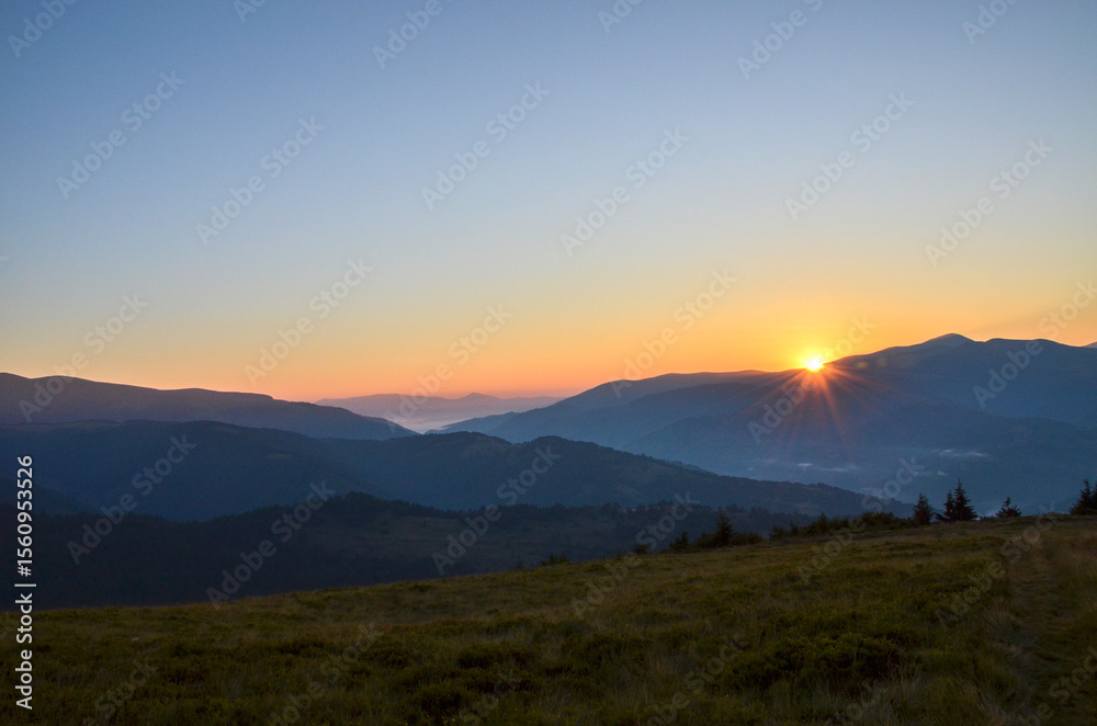 Obraz premium Breathtaking view of the sunrise illuminating hills, mountains and lush green valley, highlighting the beauty of nature's landscapes in serene and tranquil morning atmosphere. Carpathians, Ukraine