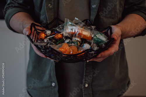 closeup of man holding halloween plate with candies for trick or treat