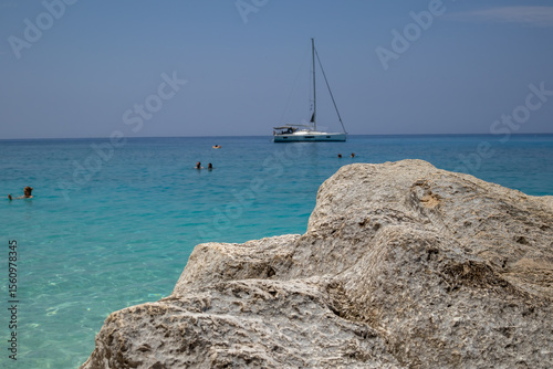 Fototapeta Naklejka Na Ścianę i Meble -  sailboat and swimmers at a stunning turquoise beach