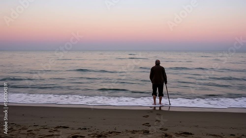 Elderly man standing on beach at sunset with serene ocean view  