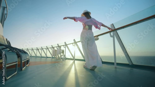 A woman joyfully enjoys her moment on the cruise ship deck, immersed in a vibrant sunset, wearing breezy clothing and a stylish hat that embodies the essence of a perfect vacation