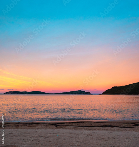 Vibrant sunset over tranquil beach captures natural beauty and serene atmosphere