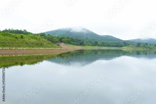 Mountain lake panorama reflecting the summer sky and forest trees, a calm and peaceful nature view
