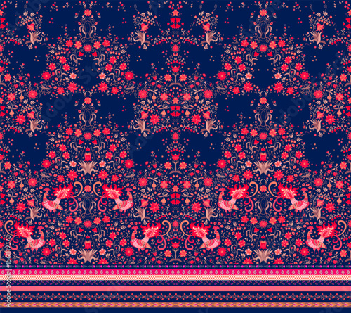 Seamless fabric print in ethnic style. Beautiful animal pattern with fabulous red peacocks among twigs, leaves, berries and flowers on a deep blue background. Decorative horizontal border.