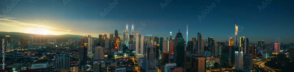 Naklejka premium Panoramic night view of Kuala Lumpur city skyline, beautiful lit with city light as the sun set behind the hills.