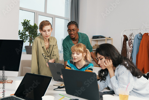 Young adult woman coworkers collaborating in modern workplace, socializing and working together, representing Gen Z business and friends in professional environment.