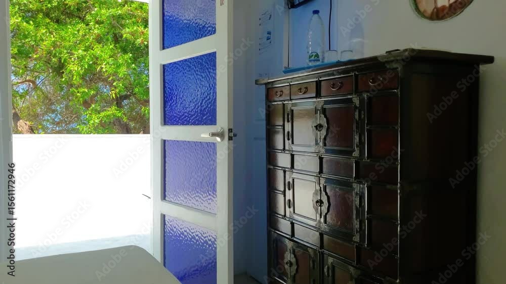 Antique Chinese Apothecary Dark wooden cabinet, indoor bedroom with green trees outside. Vintage