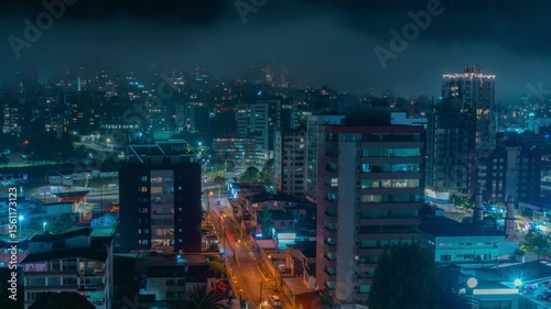 Time-lapse of panoramic night view of clouds covering buildings in the northern part of Quito with car traffic circulating in the streets - Ecuador