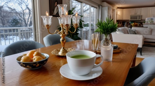 Matcha is served in a hand--painted bowl, next to persimmons and pine branches