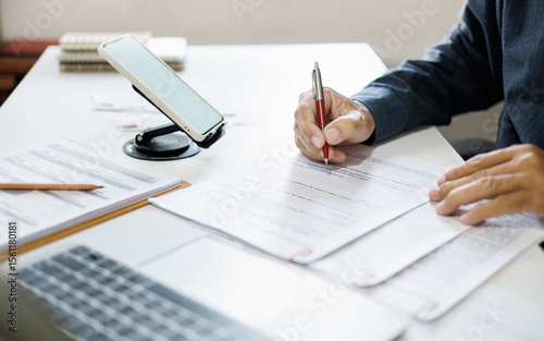 asian businessman working on desk reading and checking financial documents and business contract before making business plan